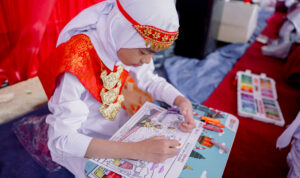 Seorang siswa dengan busana adat sedang serius mewarnai gambar bertema _Nusantara Bicara MotoGP Pertamina Enduro Mandalika_ di SDN 39 Palembang (Dok. Humas Pertamina Enduro / Seputarsumatera.com)