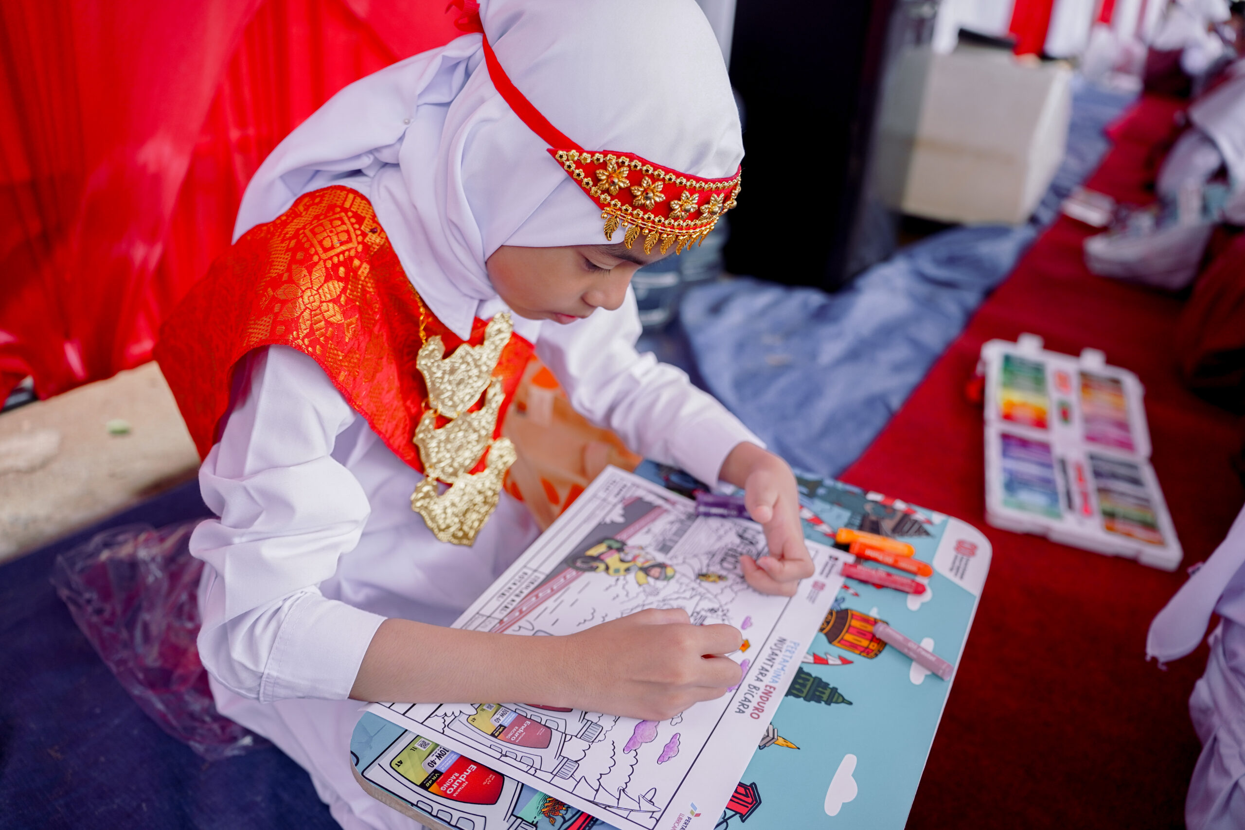 Seorang siswa dengan busana adat sedang serius mewarnai gambar bertema _Nusantara Bicara MotoGP Pertamina Enduro Mandalika_ di SDN 39 Palembang (Dok. Humas Pertamina Enduro / Seputarsumatera.com)