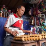Ketut Cedung memainkan alat musik Rindik, di depan lapak jualan aksesoris khas Bali yang dijajakannya Ketut Cedung memainkan alat musik Rindik, di depan lapak jualan aksesoris khas Bali yang dijajakannya