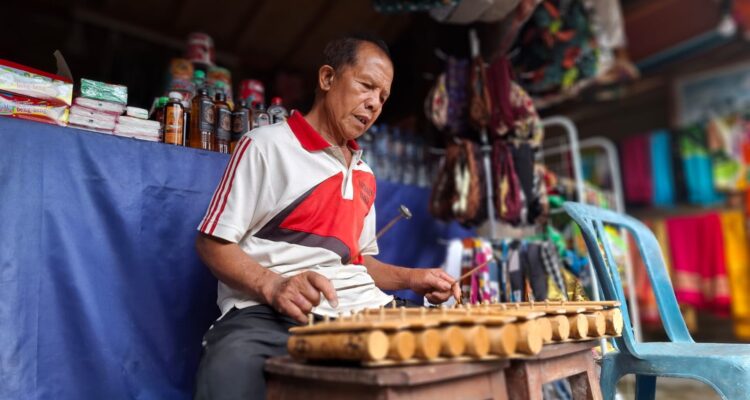 Ketut Cedung memainkan alat musik Rindik, di depan lapak jualan aksesoris khas Bali yang dijajakannya Ketut Cedung memainkan alat musik Rindik, di depan lapak jualan aksesoris khas Bali yang dijajakannya