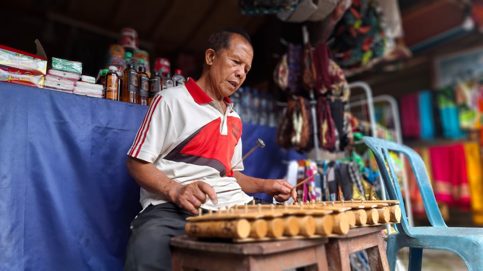 Ketut Cedung memainkan alat musik Rindik, di depan lapak jualan aksesoris khas Bali yang dijajakannya