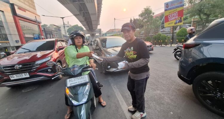Mpit,.Ketua Yayasan Kawan Lamo Galo Sumsel saat membagikan masker ke pengendara sepeda motor (Dok. Humas Yayasan Kawan Lamo Galo Sumsel)
